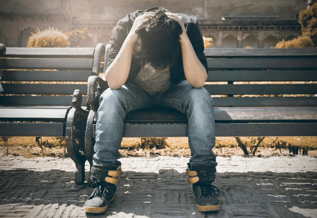 Man sitting alone on a bench in Agra, displaying signs of stress and loneliness.